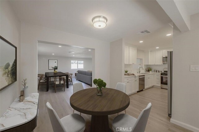 dining space with sink and light hardwood / wood-style flooring