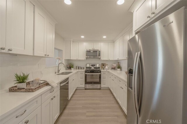 kitchen with stainless steel appliances, light hardwood / wood-style floors, white cabinets, and sink