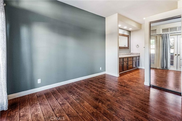 empty room with dark wood-style flooring and baseboards