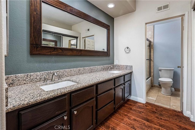 full bathroom with visible vents, a sink, toilet, and wood finished floors