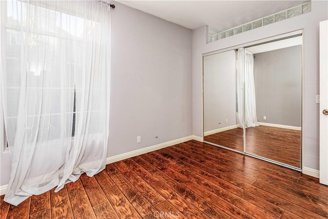 unfurnished bedroom with a closet, wood finished floors, and baseboards