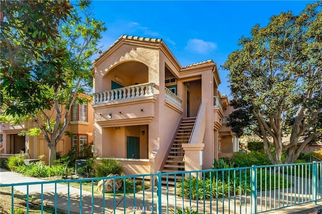 mediterranean / spanish-style house featuring stairs, fence, and stucco siding