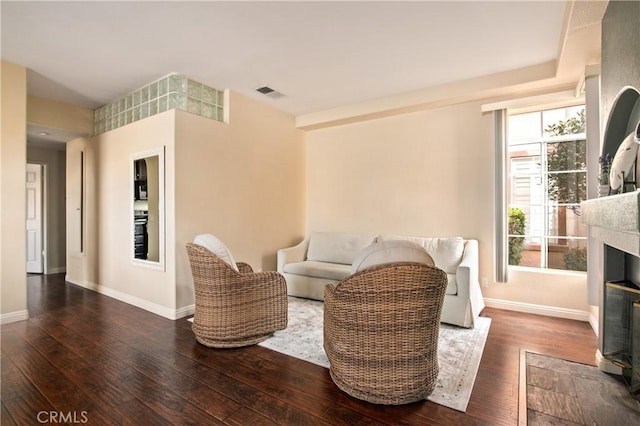 living room with a fireplace with flush hearth, hardwood / wood-style flooring, and baseboards