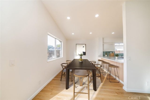 dining space with a wealth of natural light, light hardwood / wood-style flooring, and lofted ceiling