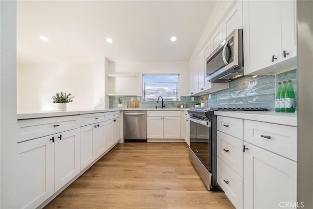 kitchen featuring light hardwood / wood-style floors, decorative backsplash, sink, stainless steel appliances, and white cabinets