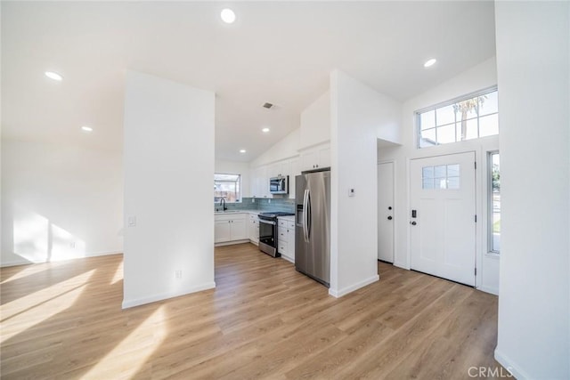 entryway featuring high vaulted ceiling, sink, and light hardwood / wood-style flooring