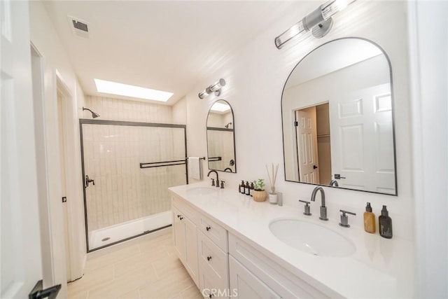 bathroom featuring tile patterned floors, a tile shower, vanity, and a skylight