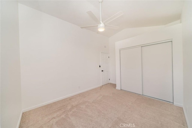 unfurnished bedroom featuring ceiling fan, a closet, light carpet, and vaulted ceiling