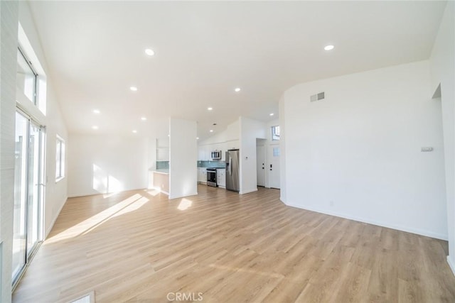 unfurnished living room with light hardwood / wood-style floors and high vaulted ceiling