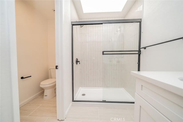 bathroom featuring toilet, a skylight, tile patterned flooring, and a shower with door