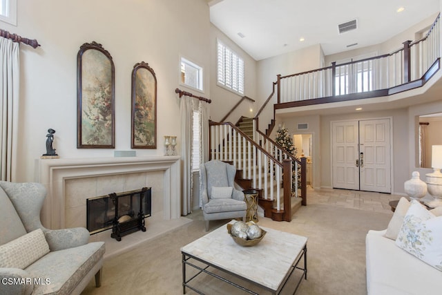 living room featuring light carpet, a tiled fireplace, and a high ceiling