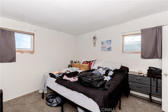 carpeted bedroom featuring a textured ceiling and multiple windows