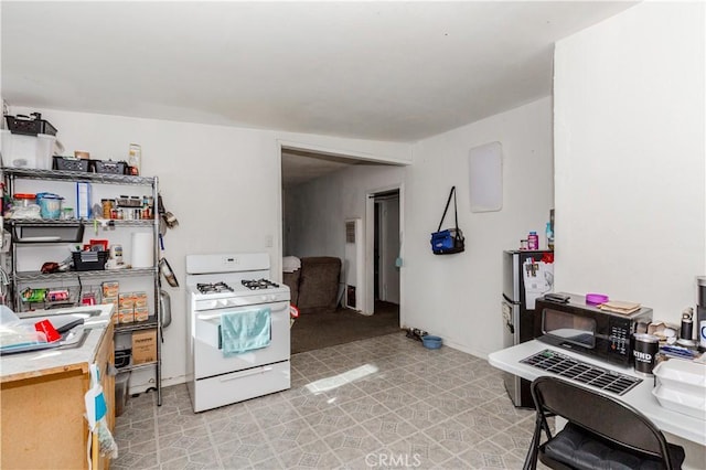 kitchen with white gas range oven and stainless steel refrigerator