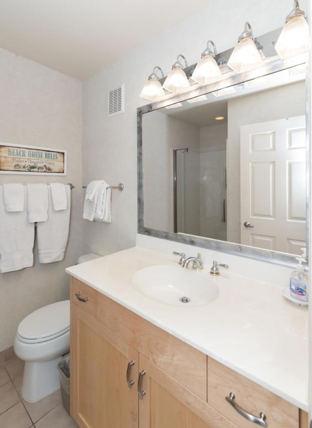 bathroom featuring toilet, tile patterned flooring, a shower with door, and vanity