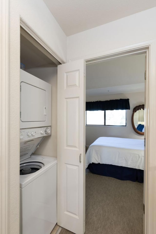 washroom featuring stacked washer / drying machine and light carpet