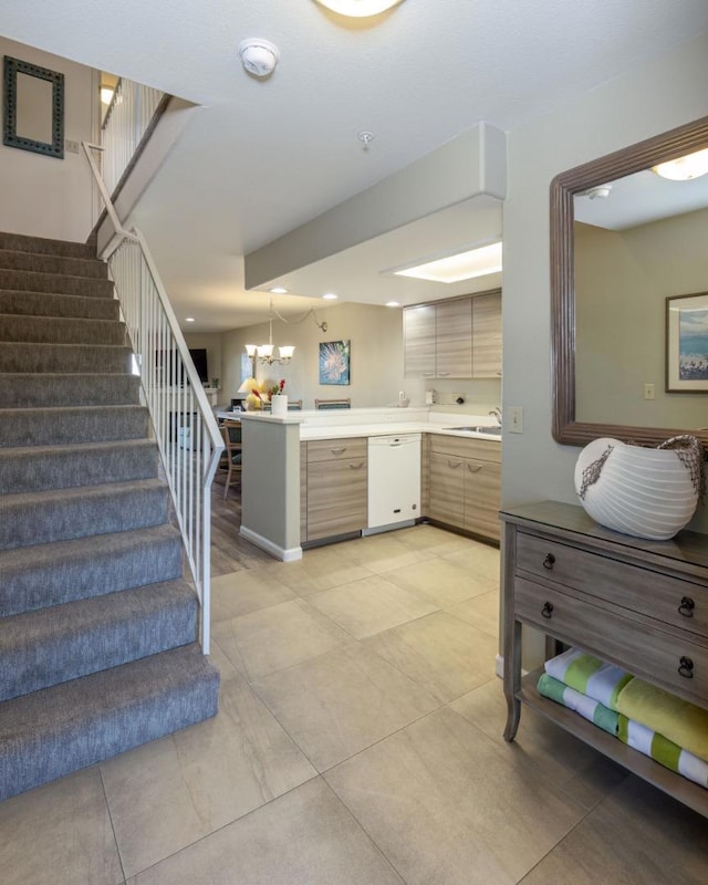 kitchen featuring kitchen peninsula, dishwasher, sink, and an inviting chandelier