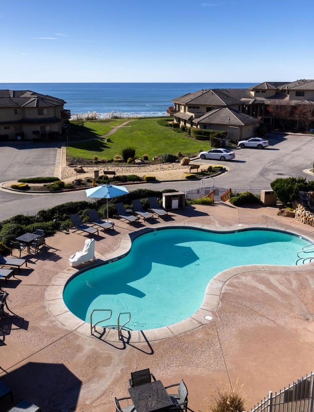 view of swimming pool featuring a water view and a patio