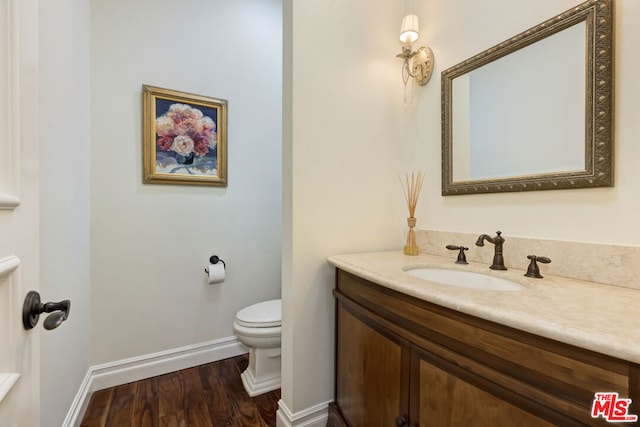 bathroom with wood-type flooring, toilet, and vanity