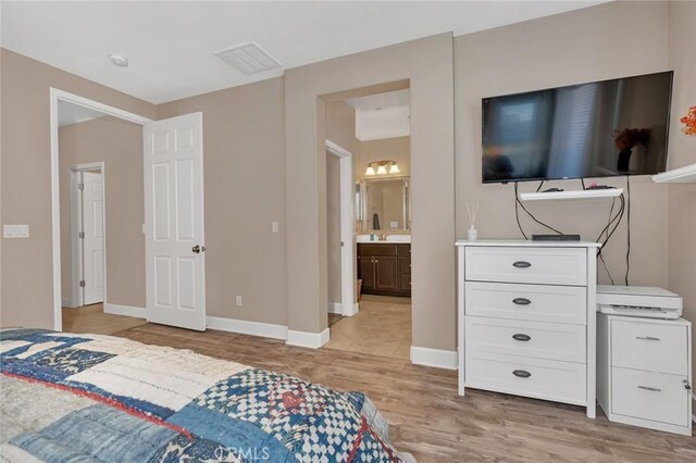 bedroom featuring ensuite bathroom and light hardwood / wood-style flooring