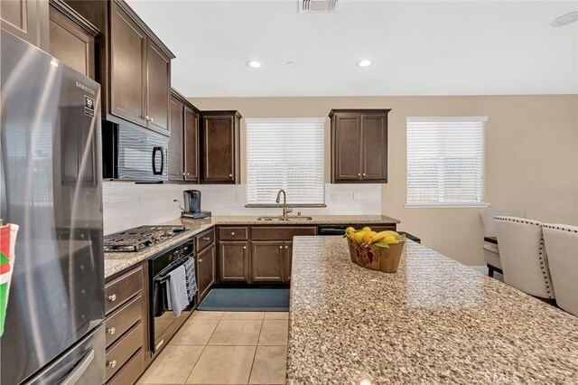 kitchen with light tile patterned floors, appliances with stainless steel finishes, sink, and light stone counters