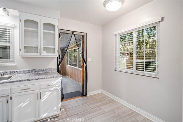 interior space featuring white cabinetry, light stone counters, and sink