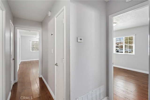 hallway featuring a textured ceiling and dark hardwood / wood-style floors