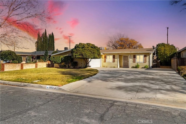 ranch-style house featuring a garage and a yard