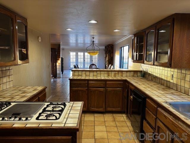 kitchen featuring tile counters, white gas cooktop, kitchen peninsula, and pendant lighting