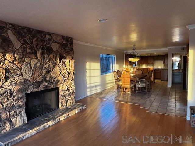 unfurnished dining area with dark hardwood / wood-style flooring, ornamental molding, and a stone fireplace