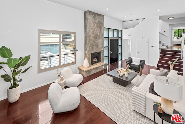 living room featuring dark wood-type flooring, crown molding, and a fireplace