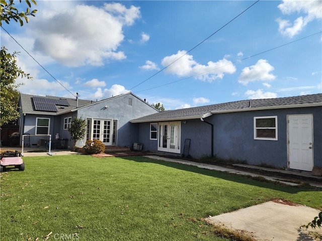 rear view of house featuring solar panels, a yard, and french doors