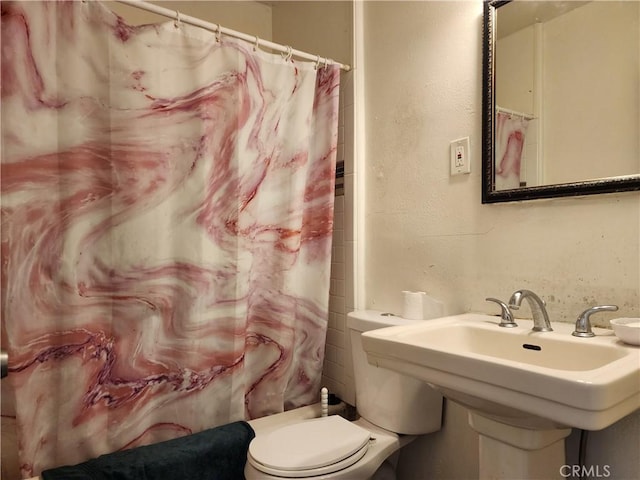 bathroom featuring sink, toilet, and a shower with shower curtain