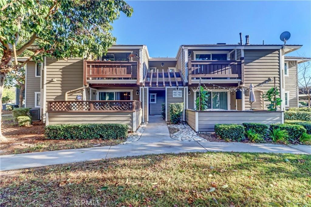 view of front of home with a balcony and a front yard