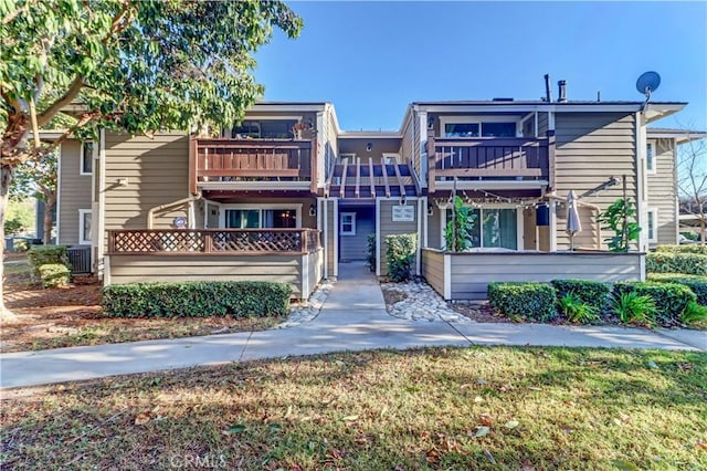 view of front of home with a balcony and a front yard