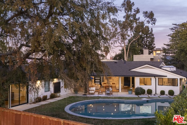 back house at dusk with a patio area