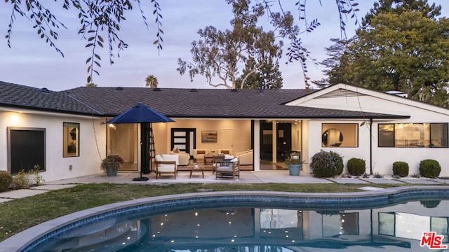 back house at dusk featuring a patio area and an outdoor living space