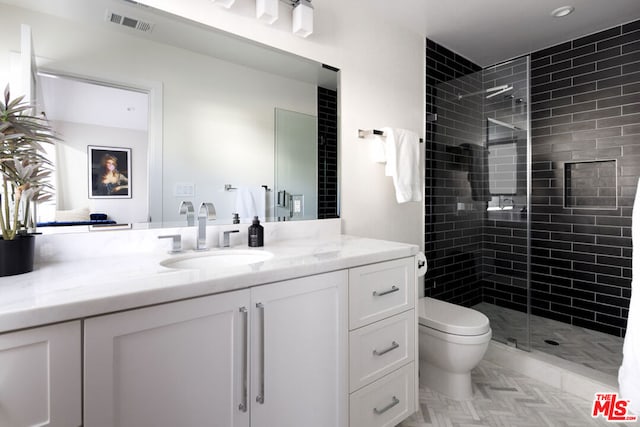 bathroom featuring toilet, a tile shower, and vanity