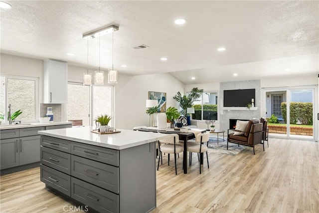 kitchen featuring sink, a large fireplace, gray cabinetry, and decorative light fixtures