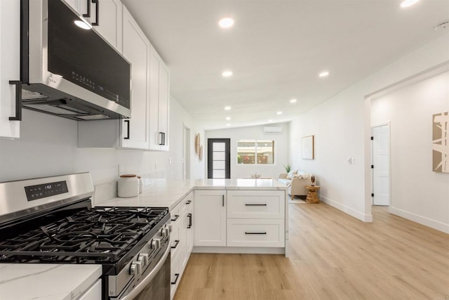 kitchen featuring white cabinets, lofted ceiling, stainless steel appliances, kitchen peninsula, and light hardwood / wood-style flooring