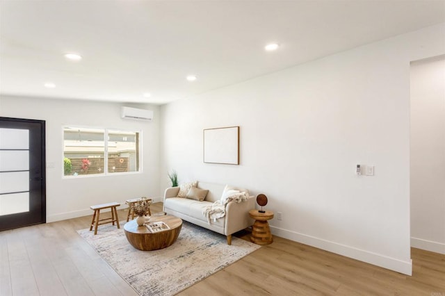 living room featuring an AC wall unit and light hardwood / wood-style floors