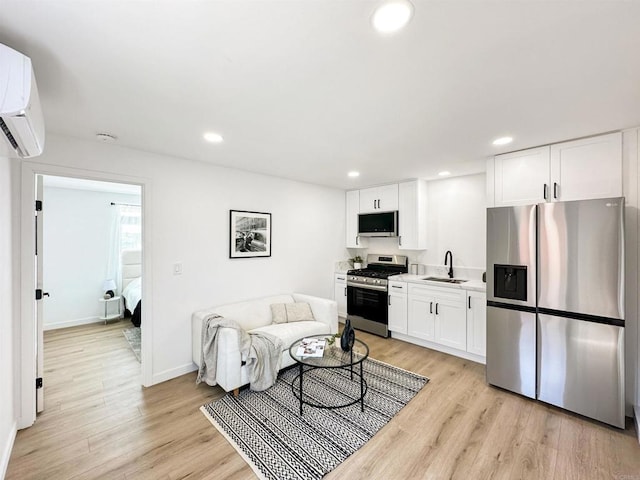 living room featuring an AC wall unit, sink, and light wood-type flooring