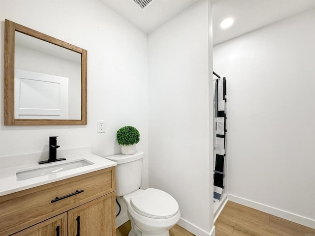 bathroom with toilet, a shower, hardwood / wood-style floors, and vanity