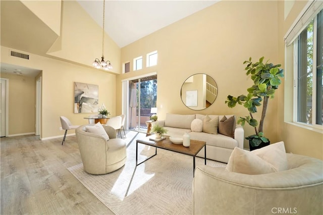 living room featuring high vaulted ceiling, plenty of natural light, a notable chandelier, and hardwood / wood-style floors