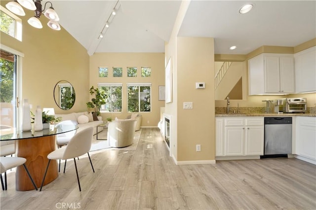 kitchen featuring light hardwood / wood-style floors, white cabinetry, stainless steel dishwasher, and a notable chandelier