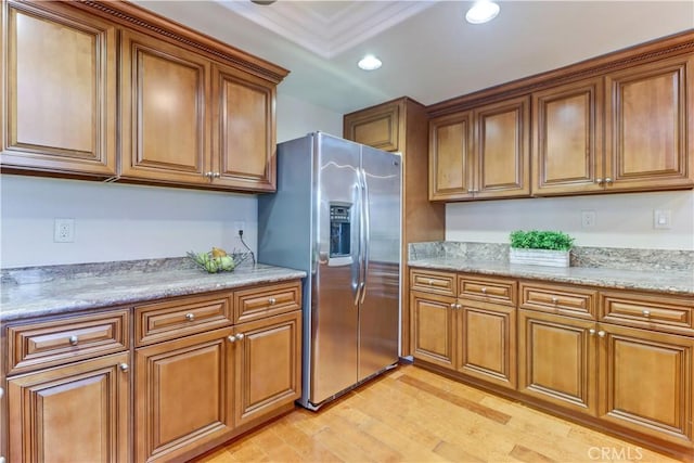 kitchen featuring light stone counters, stainless steel fridge with ice dispenser, and light wood-type flooring