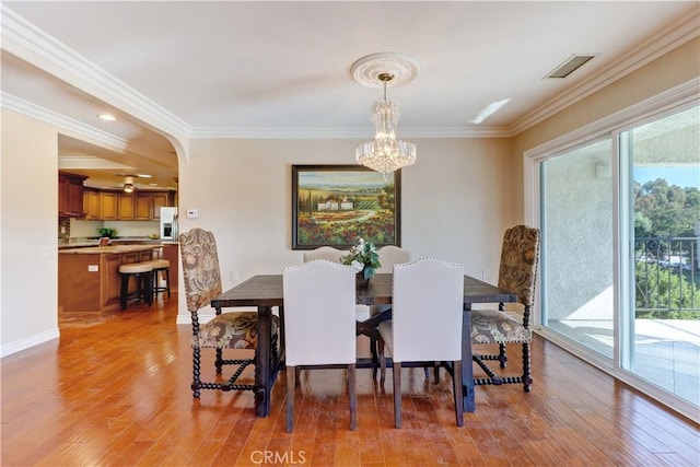 dining area featuring plenty of natural light, an inviting chandelier, ornamental molding, and hardwood / wood-style floors