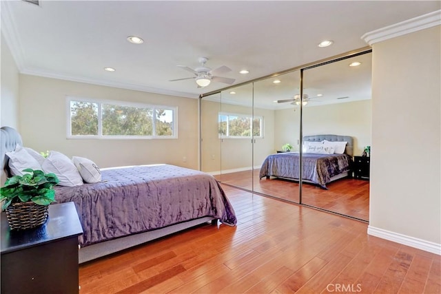 bedroom with ceiling fan, hardwood / wood-style floors, ornamental molding, and multiple windows