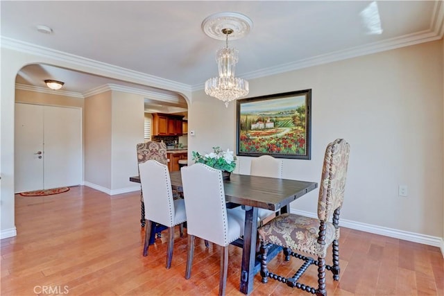 dining room with an inviting chandelier, crown molding, and light hardwood / wood-style flooring