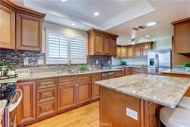 kitchen with a kitchen island, stainless steel appliances, sink, light wood-type flooring, and ceiling fan