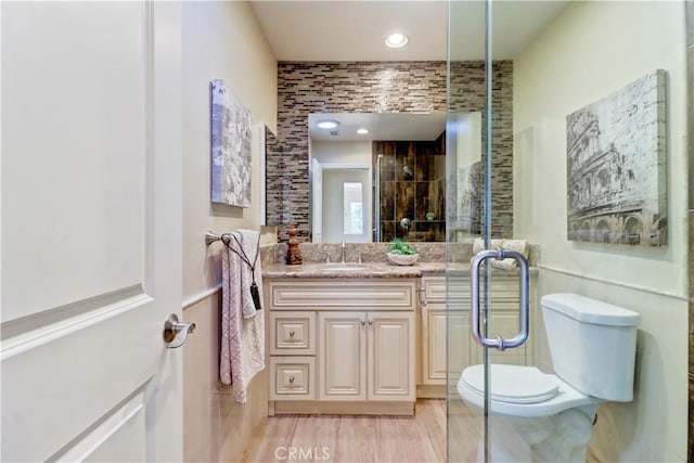 bathroom featuring toilet, hardwood / wood-style floors, an enclosed shower, and vanity